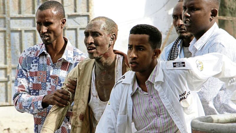 INJURED: Somali men help a civilian wounded in a suicide car bomb attack on a hotel in Mogadishu, Somalia  Picture: Farah    Abdi Warsameh/                    AP 