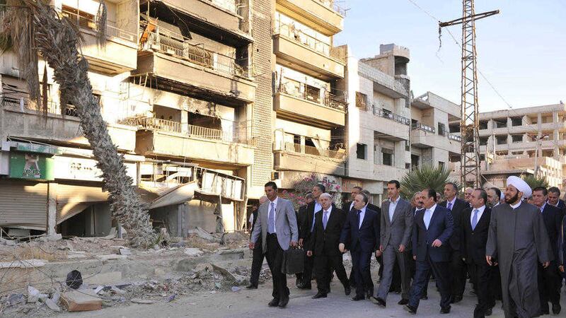 Syrian President Bashar Assad, centre, walks on a street with officials after performing the morning Eid al-Adha prayers in Daraya, a blockaded Damascus suburb in Syria.
