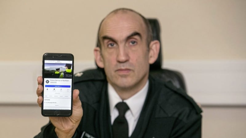 Chief Superintendent Simon Walls holds up a phone showing the force's Facebook page. Picture by Liam McBurney, Press Association