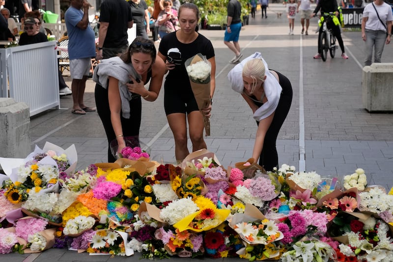 Three women place flowers as a tribute near the crime scene at Bondi Junction in Sydney (Rick Rycroft/AP)