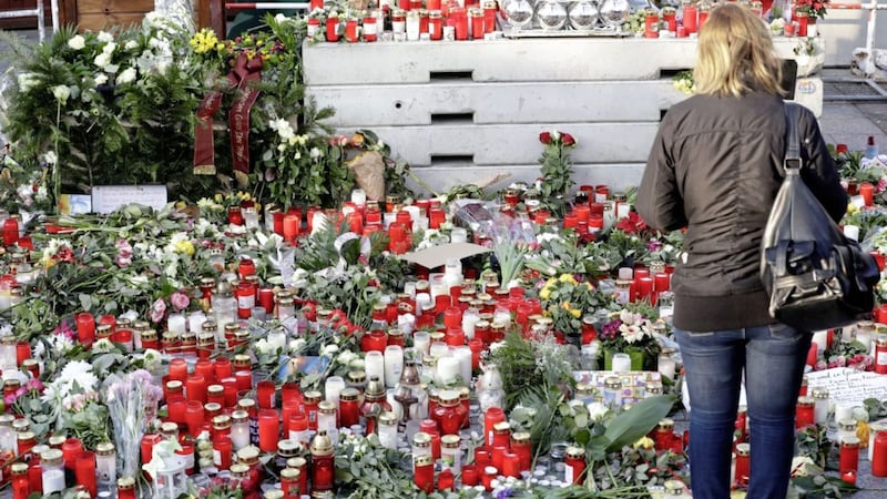 Candles burn between flowers in Berlin two days after a truck ran into a crowded Christmas market nearby and killed several people Picture by Michael Sohn/AP 