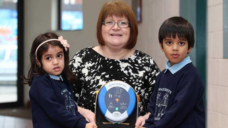 St Matthew's Nursery pupils Angela Khatri and Boga Likhith Vihaan with Bernie McConnell-Black and the newly-installed defibrillator in Short Strand Community Centre in Belfast. Picture by Mal McCann