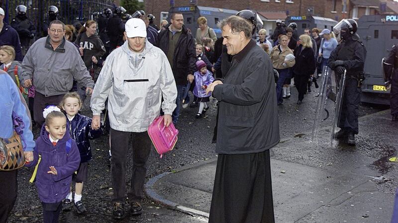 Fr Aidan Troy with parents and children outside the Holy Cross school. Picture Brendan Murphy 