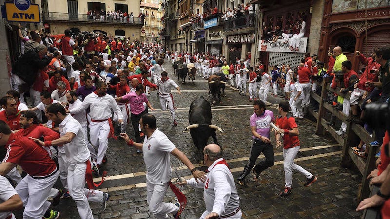 Revelers run around fighting bulls during the seventh day of the running of the bulls at the San Fermin Festival, in Pamplona, northern Spain PICTURE: Alvaro Barrientos/AP 