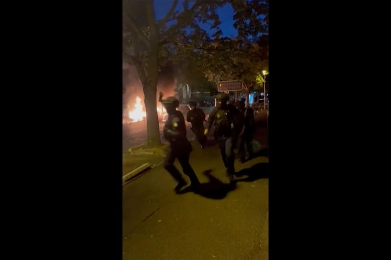 Police officers try to control people on a street in Nanterre, France