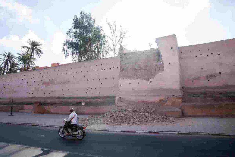 A man drives past a damaged wall of the historic Medina of Marrasech