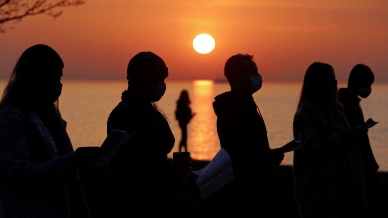 Parishioners, silhouetted against the rising sun, gather and pray during an Easter sunrise service held by Park Community Church at North Avenue Beach in Chicago on Easter Sunday. Picture by AP Photo/Shafkat Anowar 