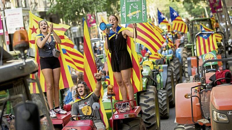 People with the estelada, or independence flags, shout slogans on top of parked tractors during a protest by farmers in Barcelona on Friday as authorities in Catalonia aim to ensure that a disputed referendum on independence from Spain will take place peacefully on Sunday PICTURE: Francisco Seco/AP 