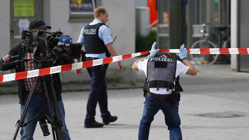 A cameraman films at the scene of a stabbing next to police officers at a station in Grafing near Munich, Germany. Picture by Matthias Schrader, Associated Press&nbsp;