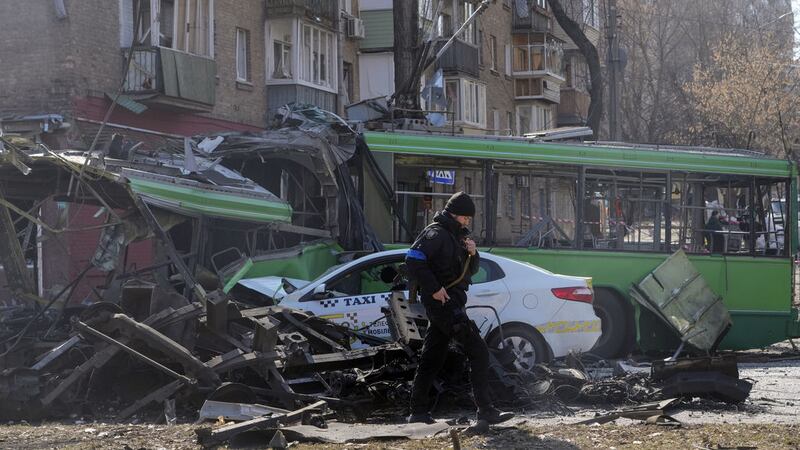 A Ukrainian soldier passes by a destroyed a trolleybus and taxi after a Russian bombing attack in Kyiv, Ukraine, Monday, March 14, 2022.<br />(AP Photo/Efrem Lukatsky)&nbsp;