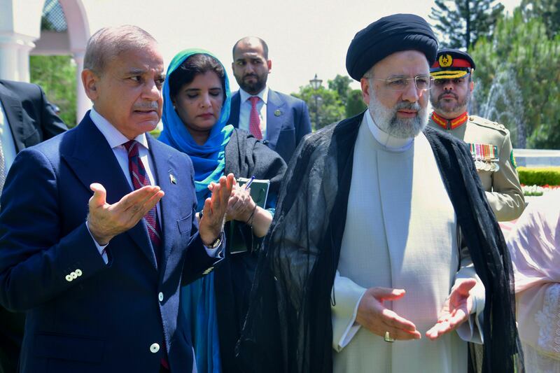 Mr Raisi and Prime Minister Shehbaz Sharif pray after planting a tree in Islamabad (Prime Minister Office via AP)