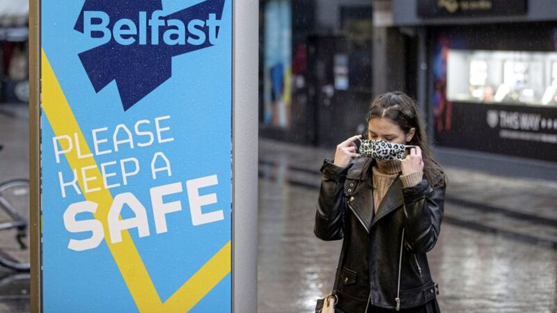 A shopper in Belfast city centre puts on a face covering - but not everyone is following the rules. Picture by Liam McBurney/PA Wire