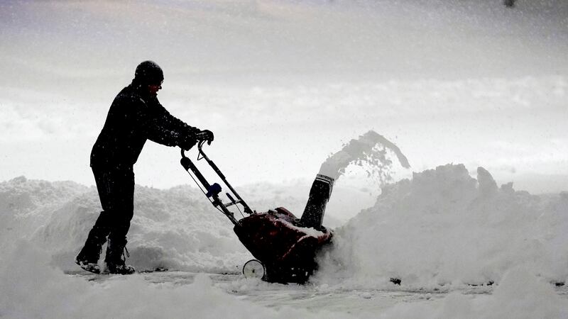 A local resident clears overnight snow from a driveway in Urbandale, Iowa (Charlie Neibergall/AP)
