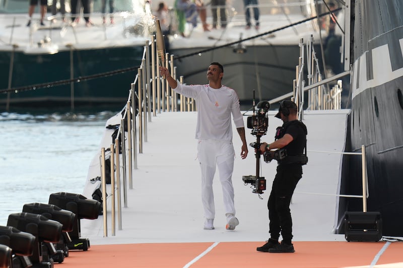 French Olympic swimmer Florent Manaudou holds the Olympic torch after leaving the Belem, the three-masted sailing ship in the Old Port of Marseille, southern France (Thibault Camus/AP)