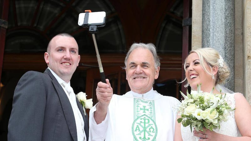 Fr Aidan Troy poses for a selfie with newlyweds Mary McLaughlin and Martin Kealey at Holy Cross Church, Ardoyne. Picture by Mal McCann 