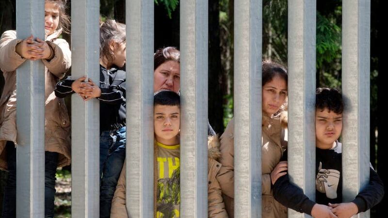 Members of a group of some 30 migrants seeking asylum are seen in Bialowieza, Poland, on Sunday, 28 May 2023 across a wall that Poland has built on its border with Belarus to stop massive migrant pressure (Agnieszka Sadowska/AP/PA)