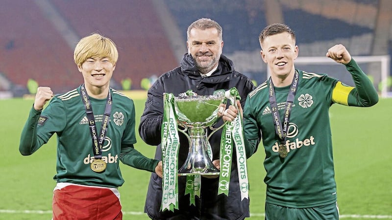Celtic manager Ange Postecoglou (centre), with star forward Kyogo Furuhashi (left) and captain Callum McGregor (right) celebrate with the first of the five domestic trophies he won, the Premier Sports Cup in December 2021. 