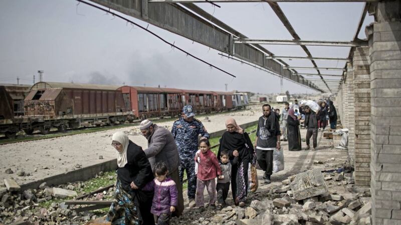Iraqi civilians flee through a destroyed train station during fighting between Iraqi security forces and Islamic State militants on Sunday. Picture by Felipe Dana, Associated Press 
