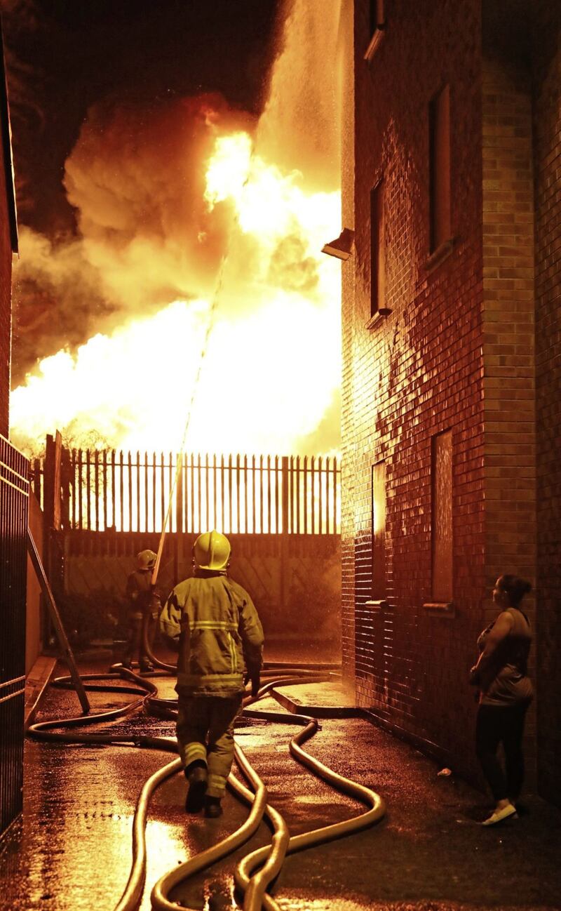 Firefighters dampen homes near a bonfire at Ravenscroft Avenue/Bloomfield Walkway in east Belfast. Picture by PA Wire