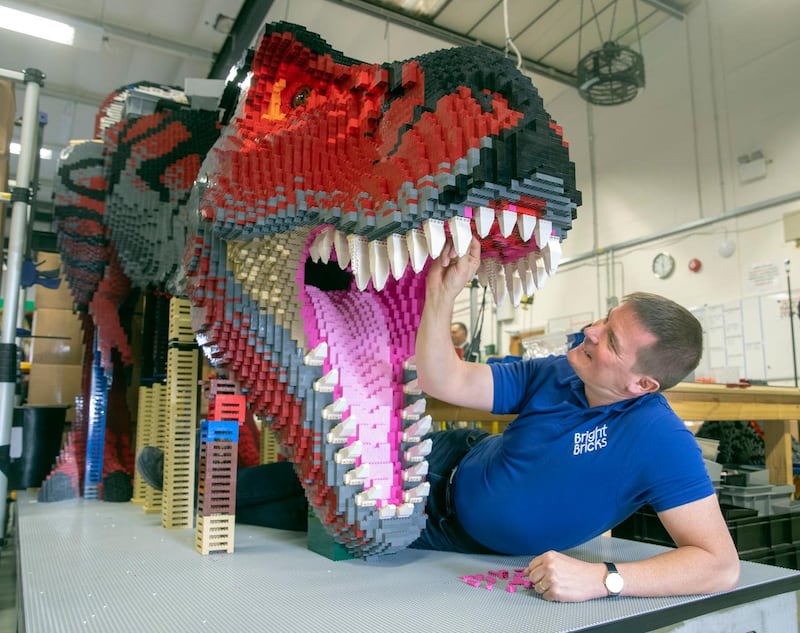 Bright Bricks member of staff Ed Diment works on a life-size T-Rex made out of Lego