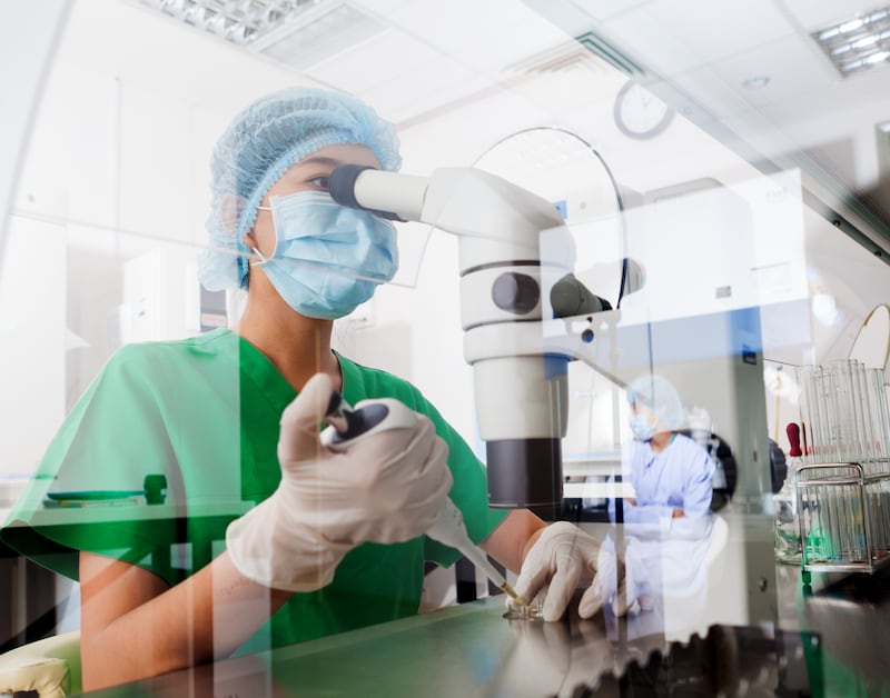 A stock image of a scientist looking through a microscope