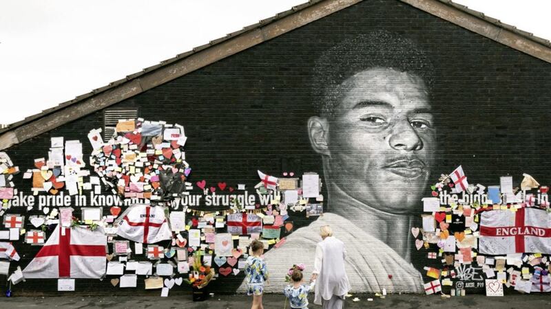 Marcella Jepson-Jones with her sister Dolly Jepson-Jones and grandmother Lynda Swire leave roses at a mural of England player Marcus Rashford in Withington, Manchester 