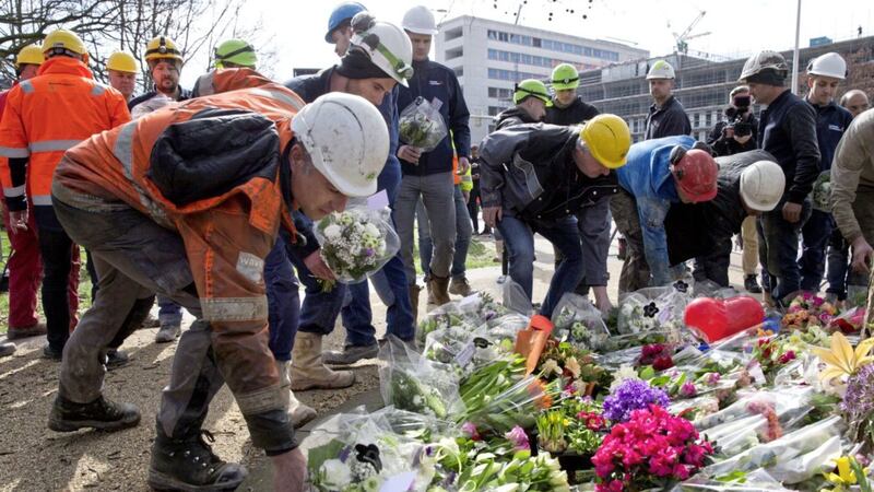 Construction workers who witnessed the tram shooting leave flowers at the site in Utrecht. Picture by Peter Dejong/AP 