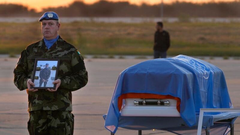 An Irish UN peacekeeper stands next to the coffin of his comrade Private Sean Rooney (Hussein Malla/AP)