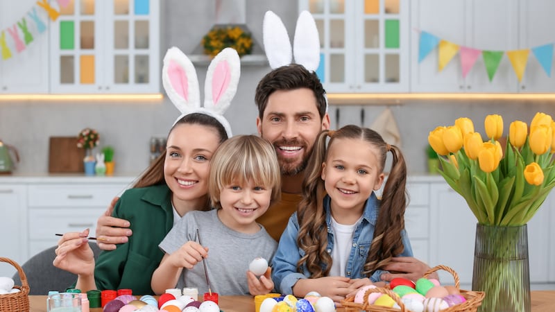 Portrait of happy family with Easter eggs at table in kitchen