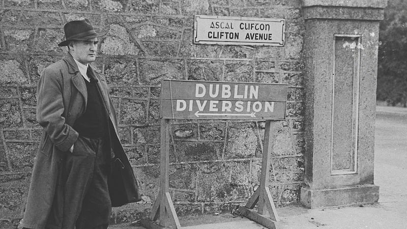 Author Brian O’Nolan, beside a diversion sign in Dublin in a black and white photograph