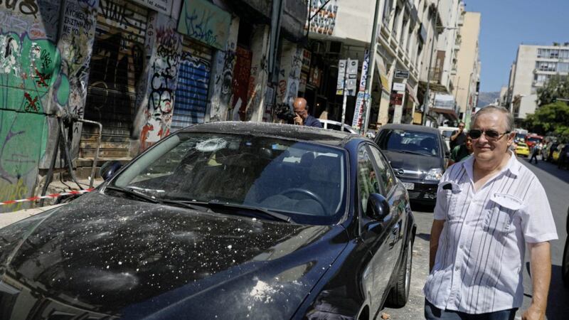 Man walks by a damaged car following an earthquake in Athens on Friday. Picture by Petros Giannakouris/AP 