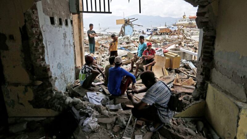 People take a break outside the shell of a house heavily damaged by the tsunami in Wani village on the outskirts of Palu, Central Sulawesi, Indonesia, on Thursday. Picture by Dita Alangkara, Associated Press 