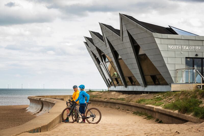 Two cyclists in front of the North Sea Observatory at Chapel St Leonards in Lincolnshire