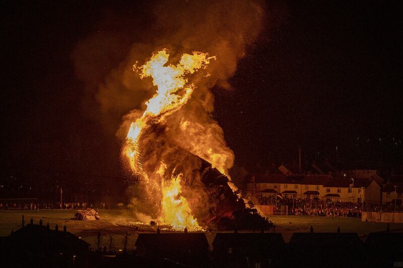 Craigyhill loyalist bonfire in Larne collapses as spectators look on. Photo: PAWire/Liam McBurney