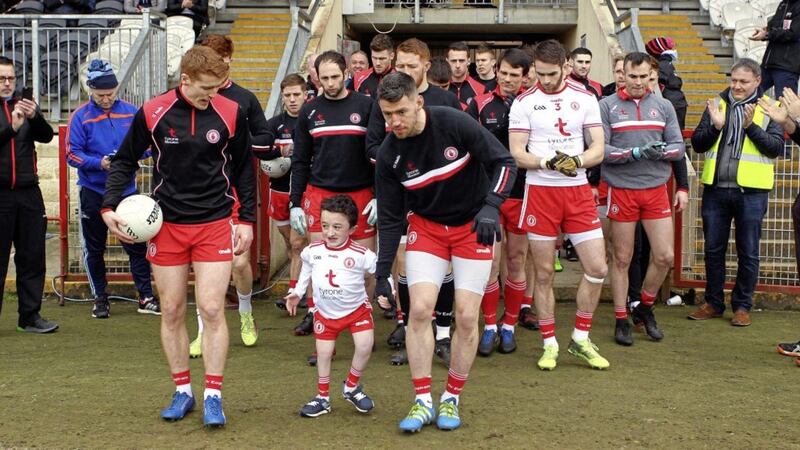A thrilled young Ciaran McAleer, who suffers from a severe brittle bone condition, leads out the Tyrone team alongside Mattie Donnelly (captain, right) and Red Hands star Peter Harte as they take to the field ahead of the Kerry clash at Healy Park, Omagh on Sunday March 25 2018. Picture: Seamus Loughran