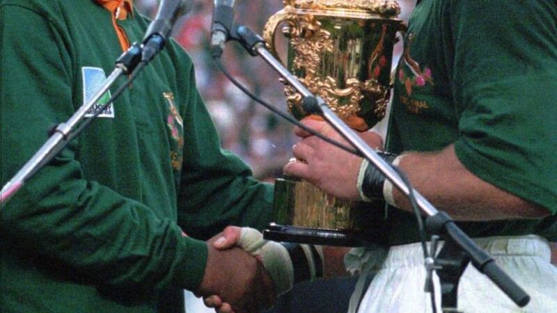 In this June 24 1995 file photo South African rugby captain Francios Pienaar (right) receives the Rugby World Cup trophy from President Nelson Mandela left who wears a South African rugby shirt after South Africa defeated New Zealand in the finals in Johannesburg. Picture by AP Photo/Ross Setford File