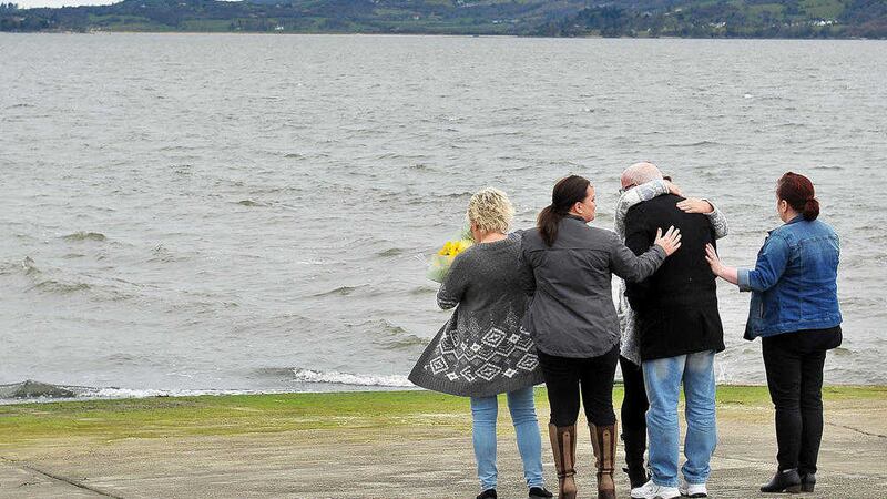 Family and friends comfort each other at the pier in Buncrana where five people lost their lives