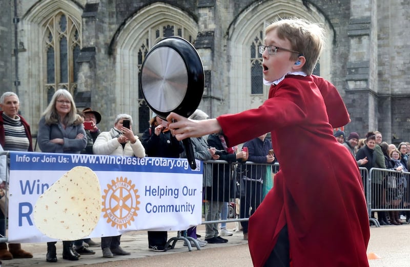 A chorister of Winchester Cathedral drops his pancake during the race