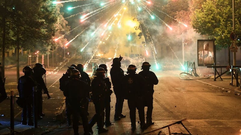 Police stand amid firecrackers on the third night of protests sparked by the fatal police shooting of a 17-year-old driver in the Paris suburb of Nanterre, France (Aurelien Morissard/AP)