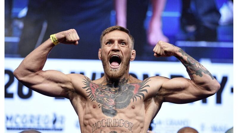 Conor McGregor, the Irish cage fighter, with his top off, showing his muscles and tattoos and cheering