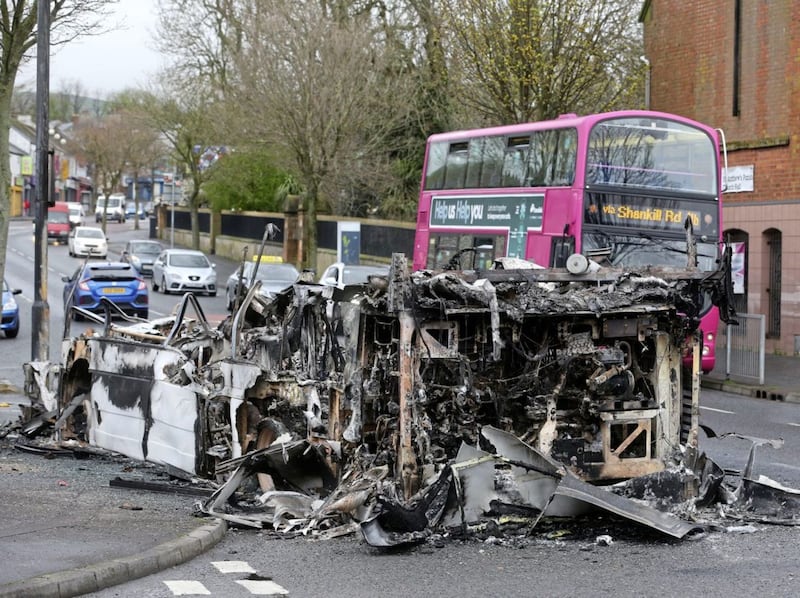 &nbsp;A bus drives past the burnt out remains of a double decker bus which was set alight during rioting in Belfast last night. Picture by Mal McCann
