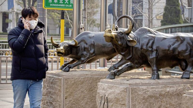 BULL MARKET: A man wearing a face mask walks past statues of bulls in Beijing. Asian stock markets fell further last week on spreading virus fears, deepening a global rout after Wall Street endured its biggest one-day drop in nine years 