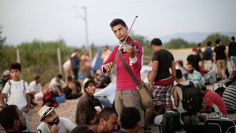 Syrian musician Rami Basisah plays for fellow refugees on the Greek-Macedonian border in 2015 Picture: Jure Erzen via PA