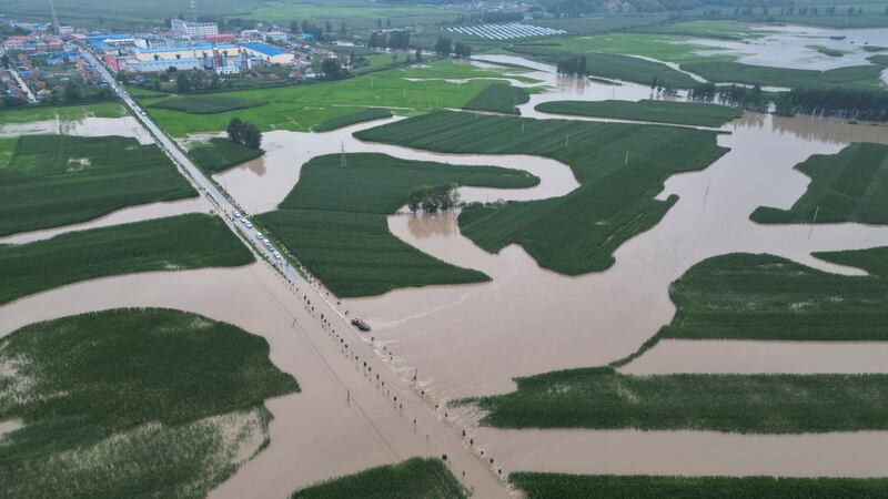 Floodwaters course through fields and roads in Kaiyuan Town of Shulan in north-eastern China’s Jilin province (Yan Linyun/Xinhua via AP)