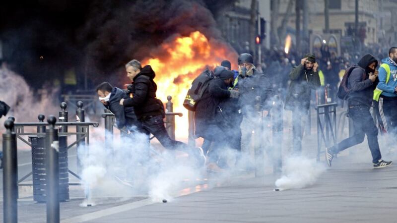 People run away from a burning car during clashes, in Marseille, southern France. Picture by AP Photo/Claude Paris