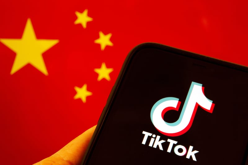 A mobile phone showing the TikTok logo in front of a China flag
