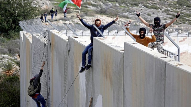Palestinian protesters climb over the separation barrier with Israel during a demonstration 