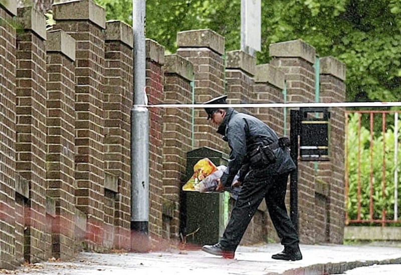 A Police officer leaves flowers on the ground close to where Thomas Devlin was murdered in 2005. 