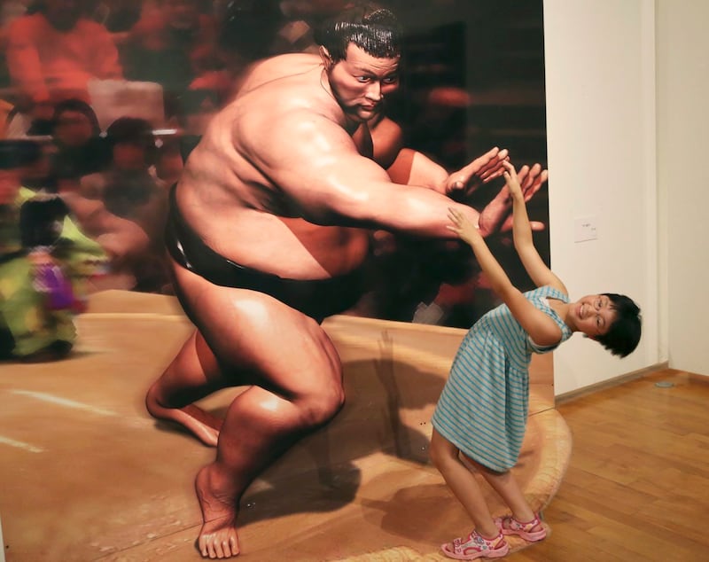 A girl poses with a 3D image at a 3D trick art exhibition by Japanese artist Masashi Hattori in Kawasaki, near Tokyo, Saturday, Aug. 5, 2017. (Koji Sasahara/AP/PA)