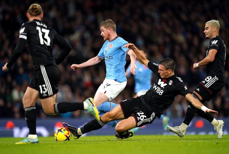 Fulham's Joao Palhinha, centre right, tackles Manchester City's Kevin De Bruyne